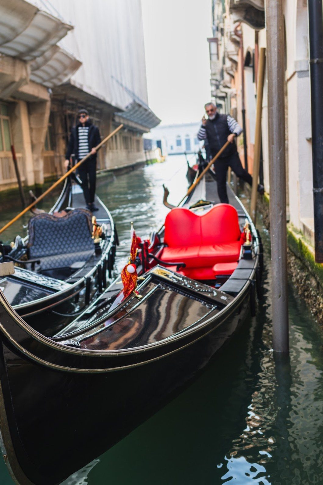 A gondolier steering his boat through a narrow Venice canal